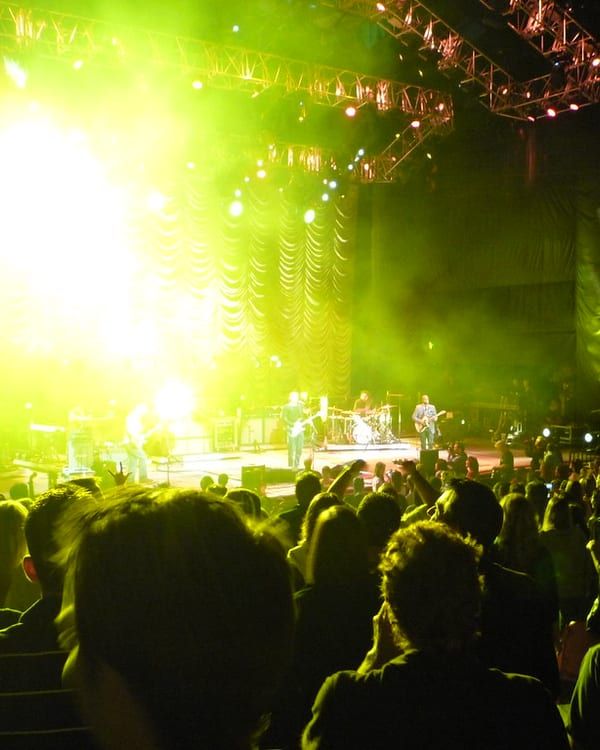 A crowd in front of a lit concert stage.