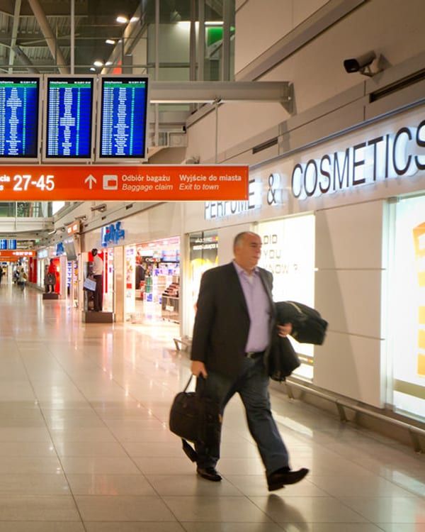 A business traveller walking through an airport terminal with bags.