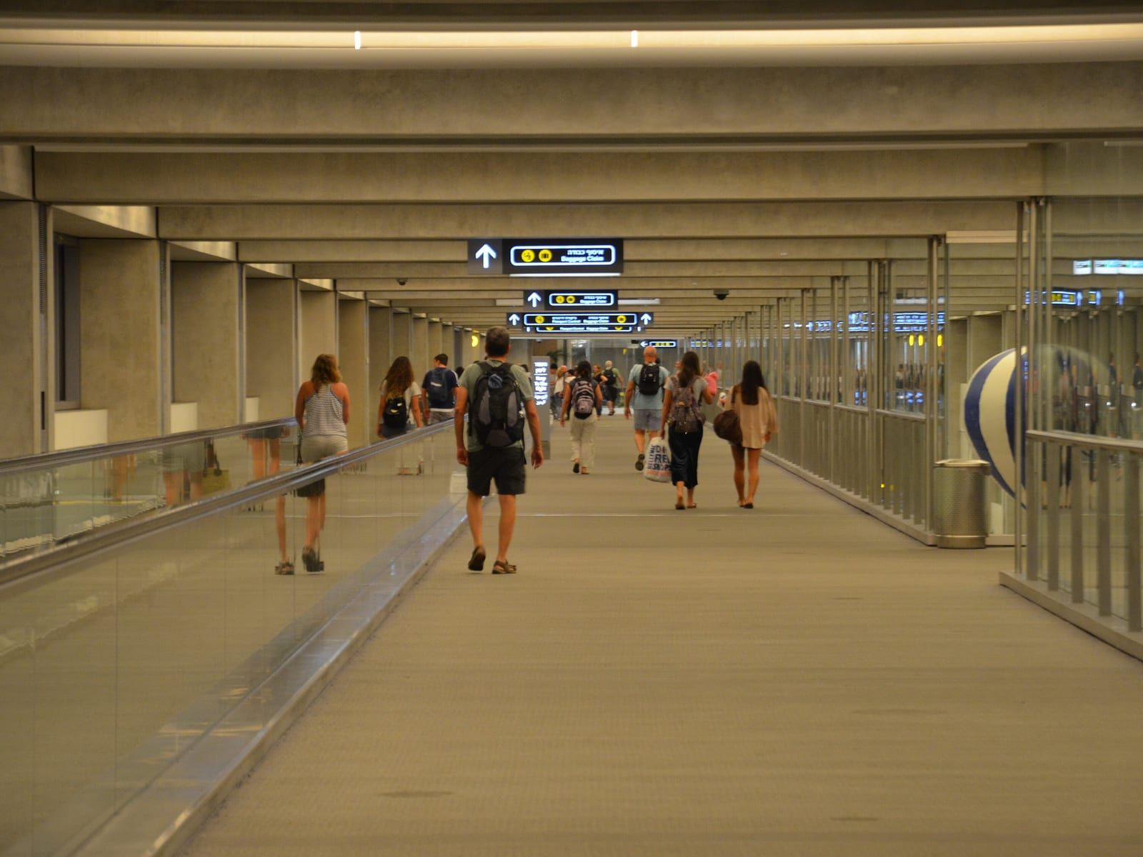 Arriving passengers walking towards baggage claim at Ben Gurion Airport.