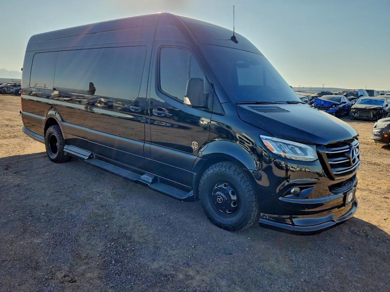 A black Mercedes-Benz Sprinter passenger van, seen from the front quarter.